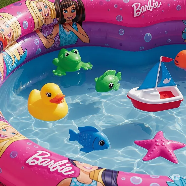 Various waterproof toys, including a rubber duck and a boat, floating inside a brightly colored Barbie inflatable pool.