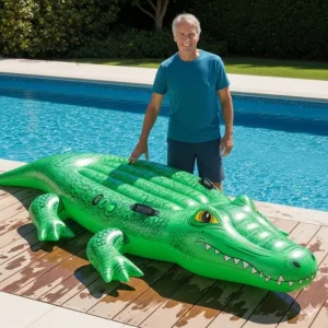 A full-sized inflatable alligator pool float next to an adult, showing its impressive length and size for easy comparison.