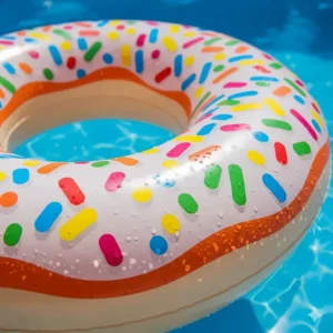 Close-up of the bright, multicolored sprinkles printed on a large, pink donut inflatable pool, highlighting its fun and whimsical design.