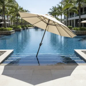 Resort-style swimming pool showing a tilted round in pool umbrella creating perfect shade over the entry steps.