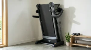 A NordicTrack folding treadmill stored vertically in the corner of a compact apartment living room to save floor space.