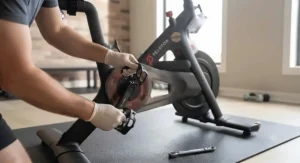 Hands checking the pedal and crank arm of a pre-owned Peloton bike during inspection.