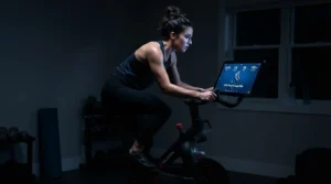 A person enjoying a late-night cycling session on an exercise bike with touchscreen in a softly lit room