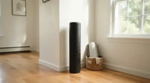 A rolled-up exercise bike mat stored compactly in the corner of a minimalist home fitness space.